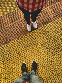 Low section of man and woman standing on tiled floor