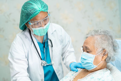 Doctor wearing flu mask consoling patient at hospital