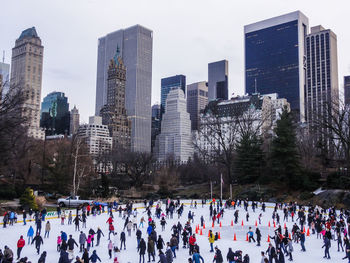 People in park against modern buildings in city during winter