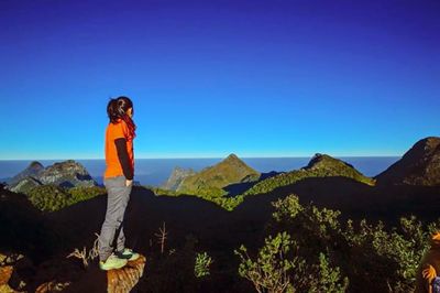 Man looking at mountains against clear blue sky