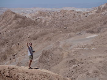 Full length of man gesturing while standing in desert