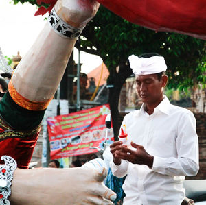 Midsection of man holding camera while standing at market