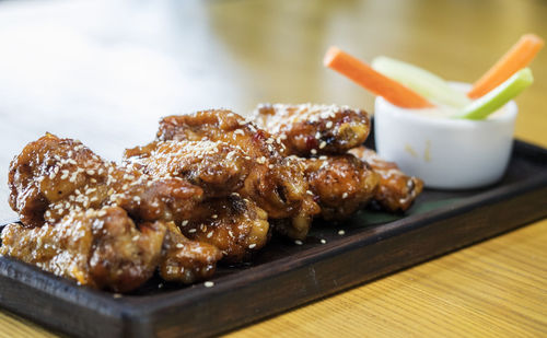 Close-up of chicken wings with sesame seeds served on wooden table