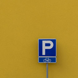 Close-up of sign board against yellow wall 