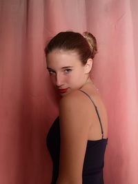 Portrait of girl standing by curtain at home