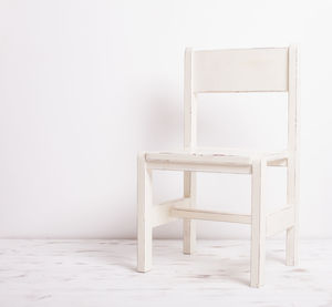 Empty chair on table against white background