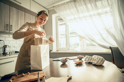 Female bakery owner packs boxes for customer's order in birthday, christmas package. food delivery