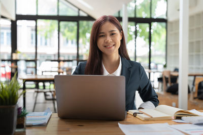 Young businesswoman using laptop while sitting on table