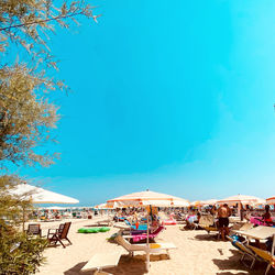 People on beach against clear blue sky