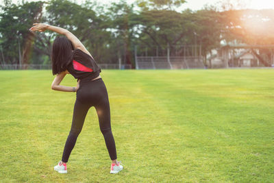 Full length of woman with arms raised on field