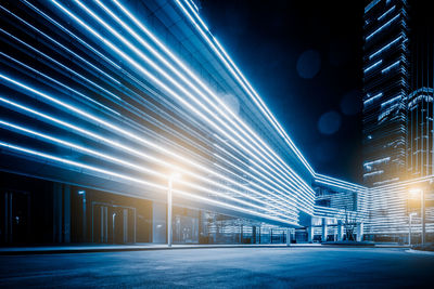 Illuminated city street against sky at night