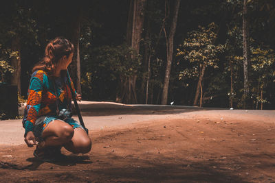 Woman sitting on street amidst trees