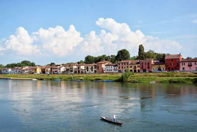 Buildings by river against sky in city