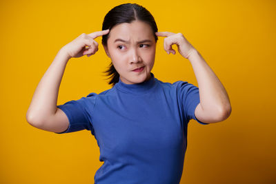 Portrait of boy standing against yellow background