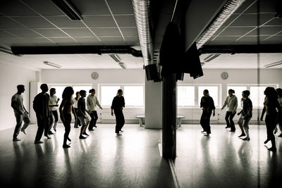 Teenage students rehearsing with female teacher in dance studio at high school