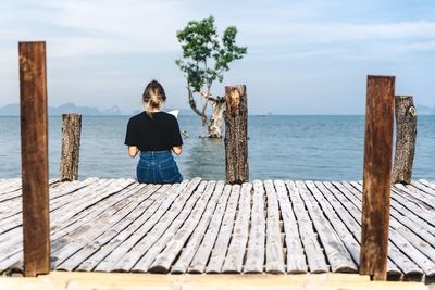 Rear view of woman standing by sea against sky