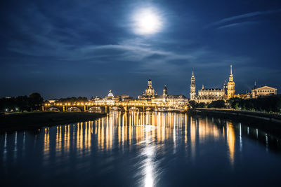 Illuminated city by river at night