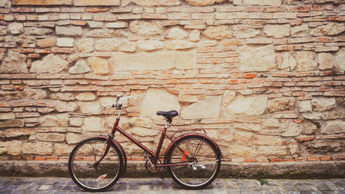 Bicycle leaning against brick wall