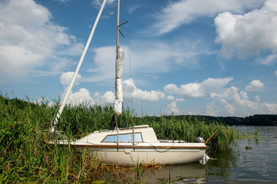 Sailboats moored on lake against sky