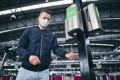 Low angle view of young man taking sanitizer on hand