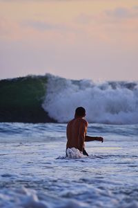 Shirtless man swimming in sea during sunset
