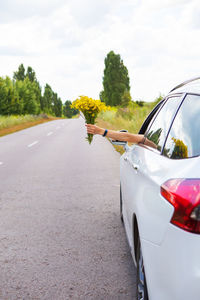 Cropped hand of woman holding flower bouquet while sitting in car