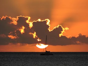 Silhouette sailboat in sea against sky during sunset