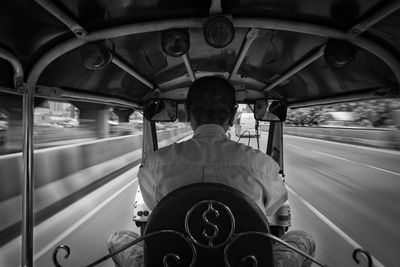 Rear view of man riding jinrikisha in city