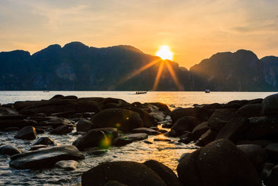 Rocks on beach against sky during sunset