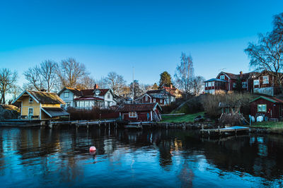 Houses reflection in river at vaxholm against blue sky