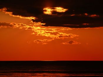 Scenic view of sea against dramatic sky during sunset