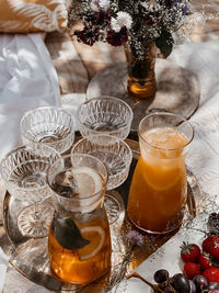 Brunch in the garden with four glasses and  two orange lemonade pitchers on a gold plate