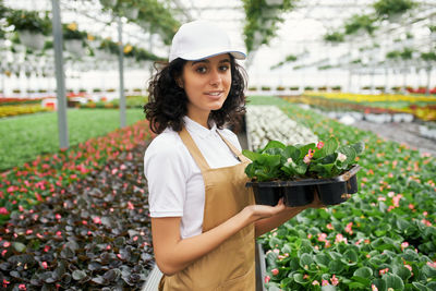 Portrait of a smiling young woman standing by plants