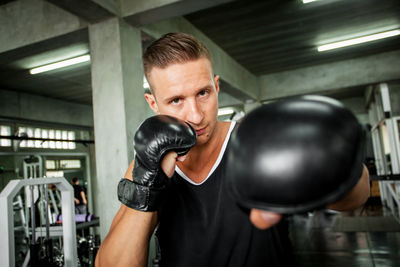 Portrait of man with boxing gloves standing in gym