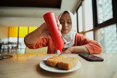 Cropped hand of woman using mobile phone on table