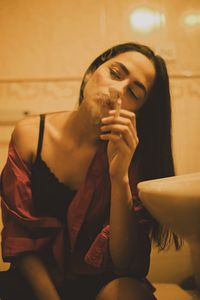 Portrait of young woman smoking cigarette in bathroom
