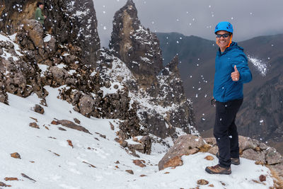 Portrait of man gesturing while standing on snow covered mountain