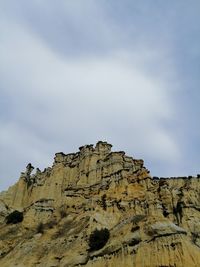 Low angle view of rocky mountain against sky