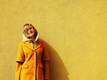 Young woman standing against wall