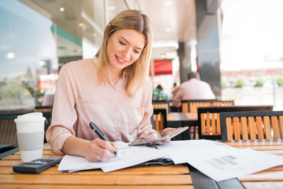 Young woman using mobile phone while sitting on table