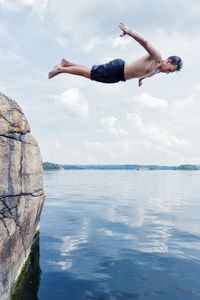 Man jumping in sea against sky