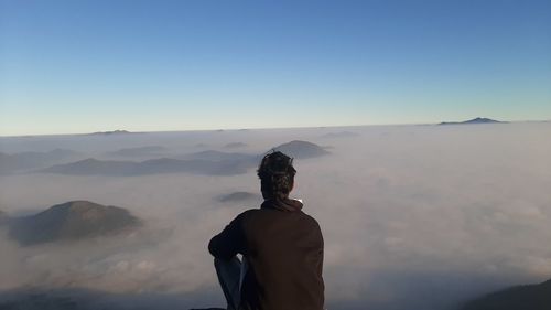 Rear view of man looking at mountains against sky