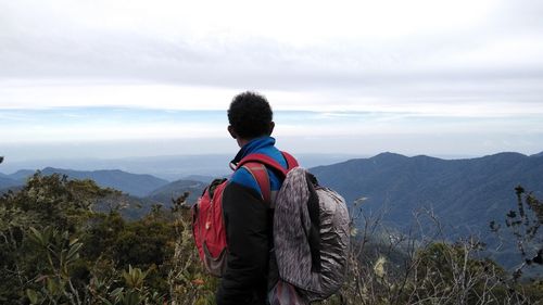 Rear view of man looking at mountains against sky