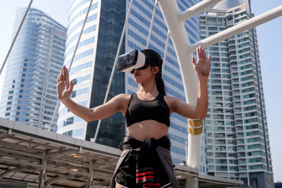 Low angle view of woman using virtual reality simulator in city