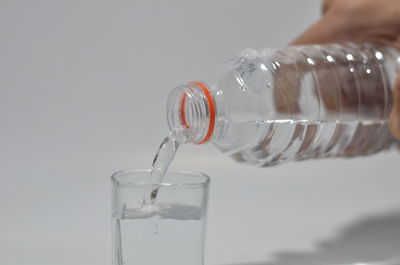 Close-up of hand pouring glass against white background
