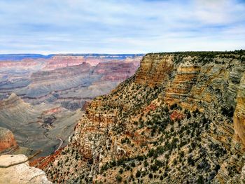 Rock formations on landscape against cloudy sky