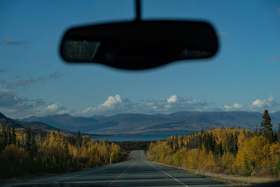 Road amidst trees against sky seen through car windshield