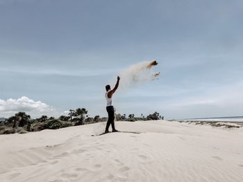 Full length of woman standing on beach against sky