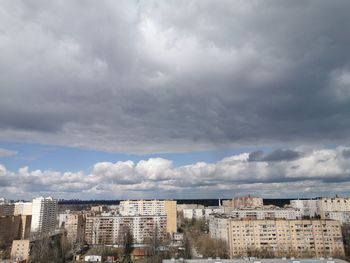 Buildings in city against dramatic sky