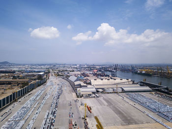 Aerial logistics commercial vehicles waiting to be load on to a car carrier ship at dockyard